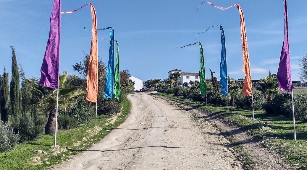 The track lined with coloured flags on poles that leads to Suryalila in Andalucia, Spain