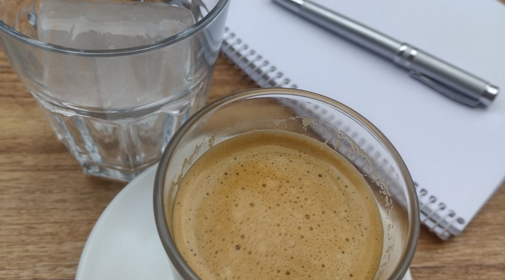 Spain writing and coffee: coffee in a glass, ice in a glass and a notebook and pen